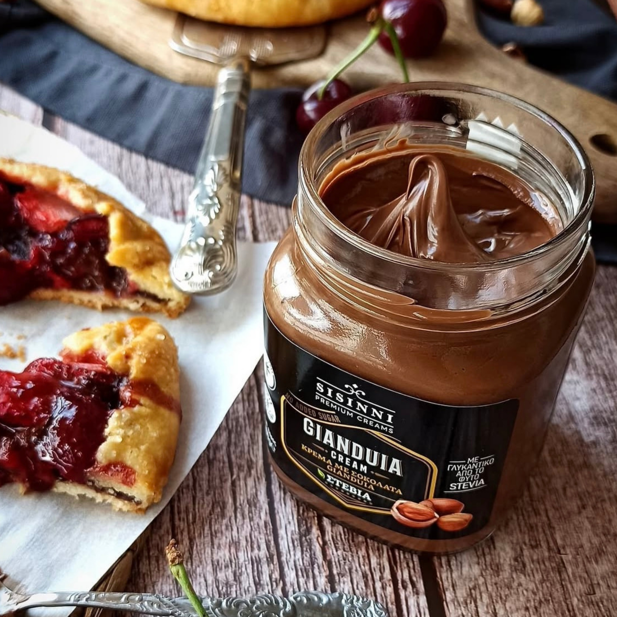 Gianduia Creme ohne Zuckerzusatz glutenfrei und ohne Palmöl im offenen Glas mit Gebäck und Kirschen Dessert Anwendung