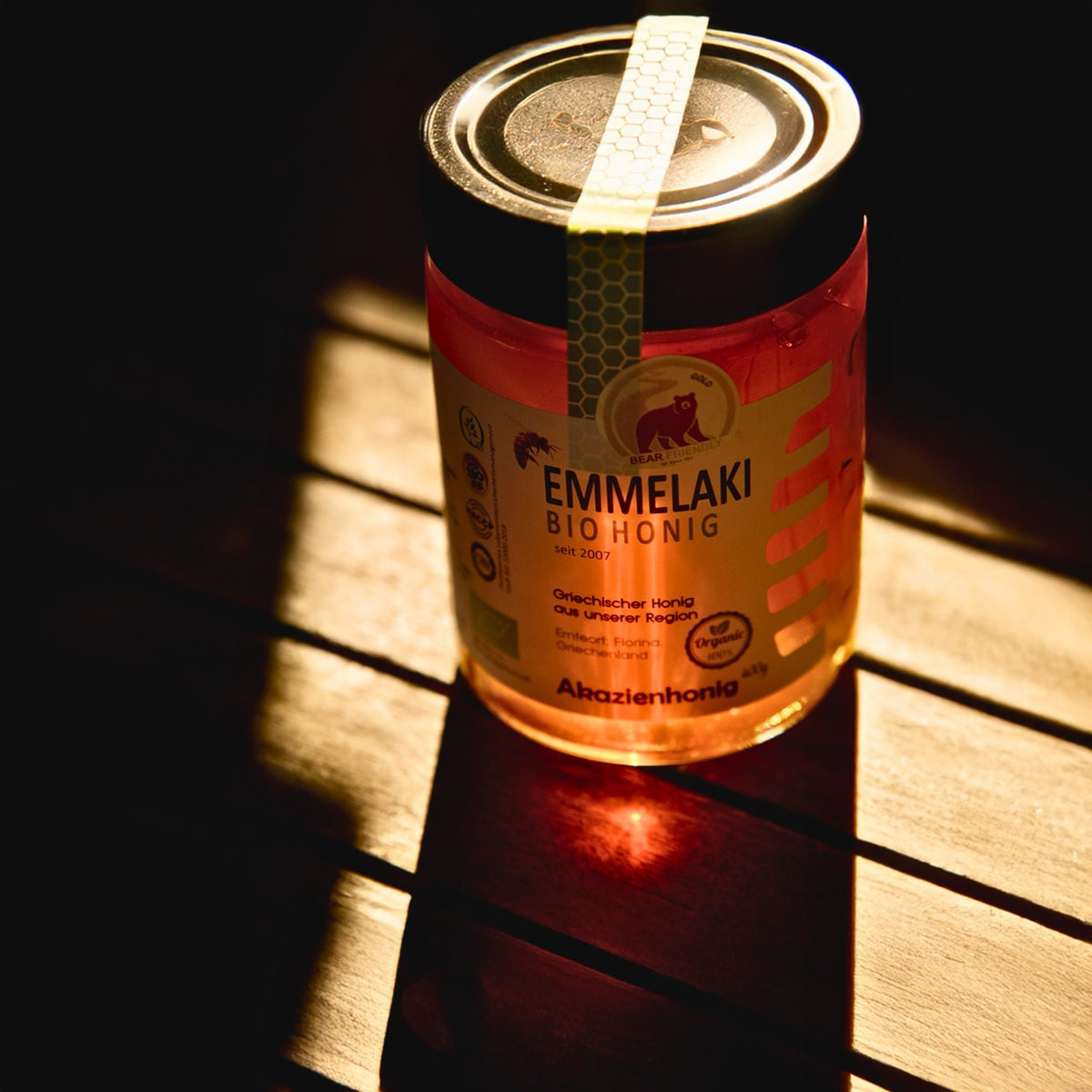 Griechischer Bio Akazienhonig im Glas von Emmelaki im warmen Sonnenlicht auf Holzoberfläche, naturreiner Premium Honig aus Griechenland