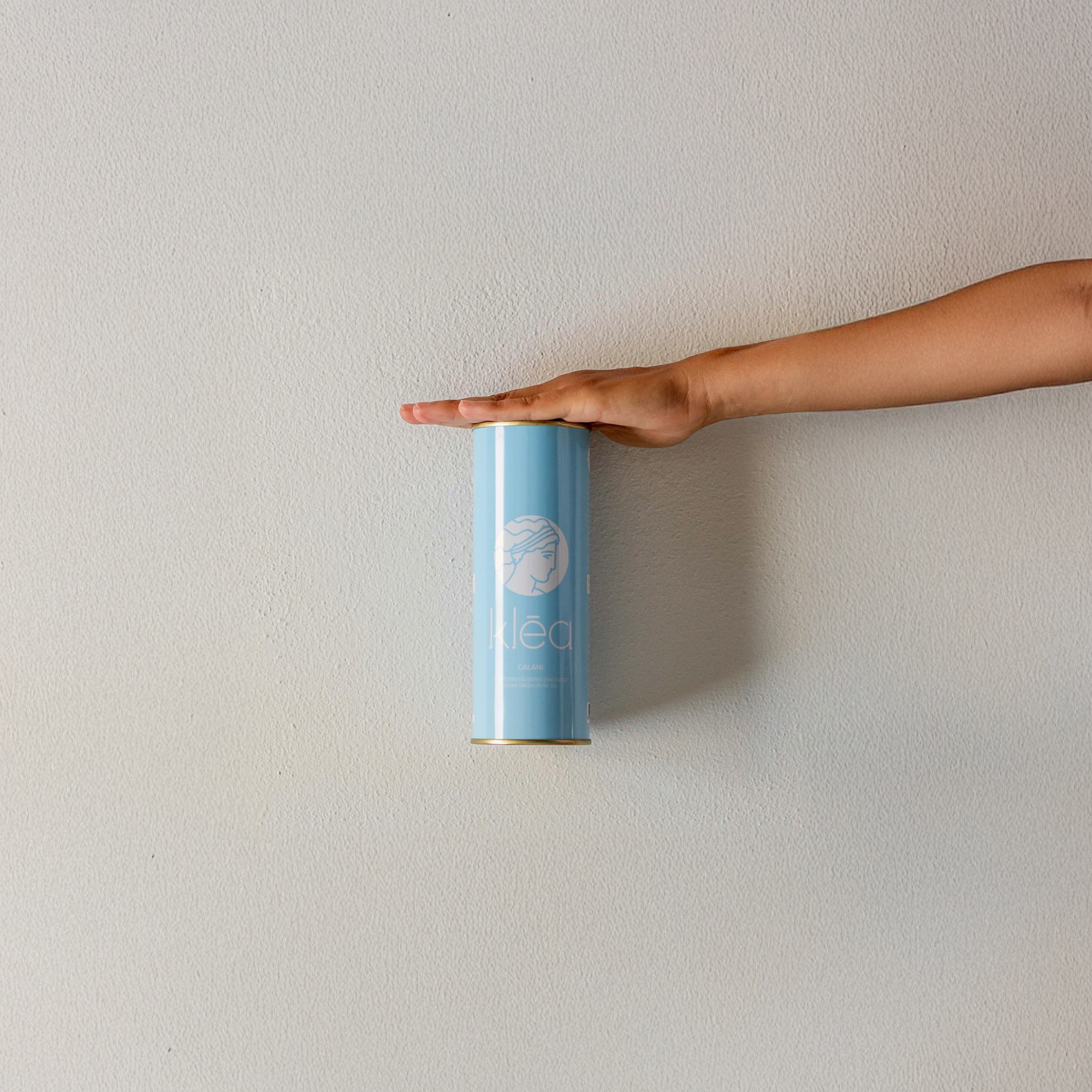 Blaue Klea Galani Olivenöl Metalldose wird auf einer Hand vor heller Wand präsentiert