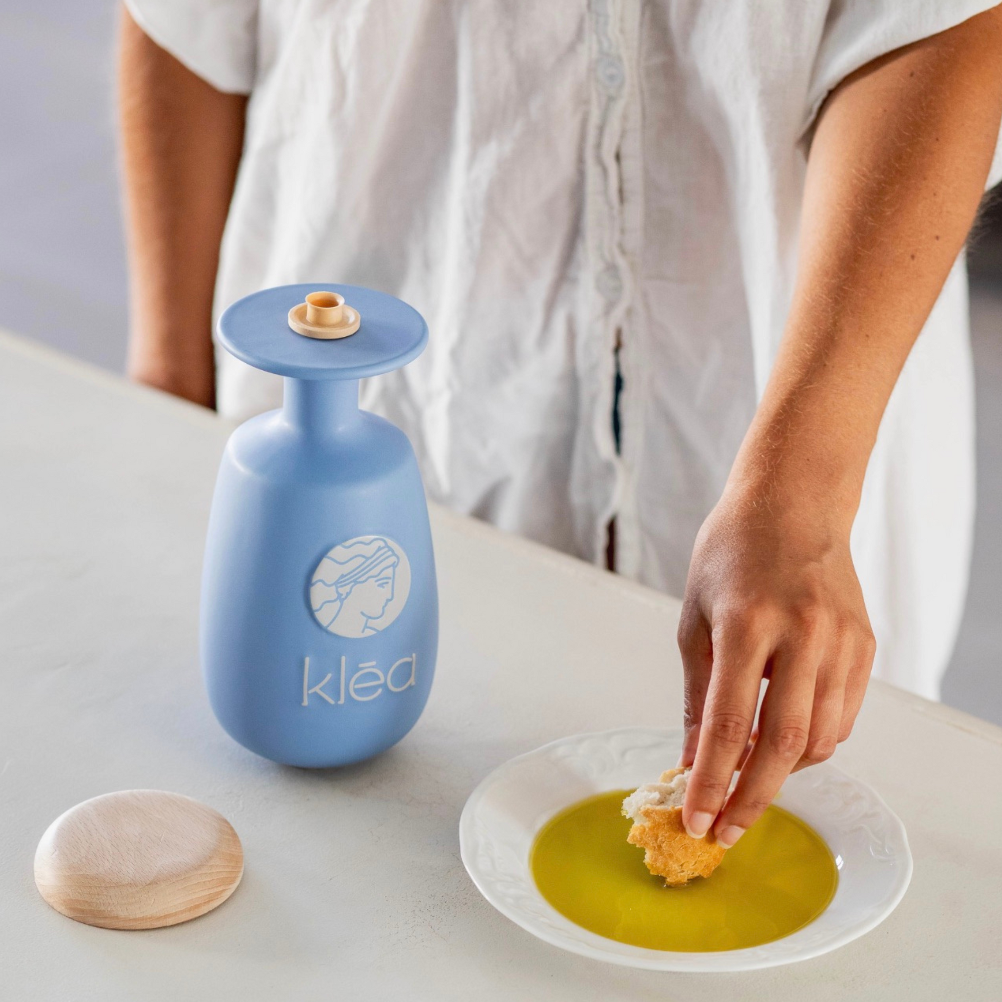 Klea natives Olivenöl extra Galani in blauer Keramikflasche neben Teller mit Olivenöl und Brot zum Dippen