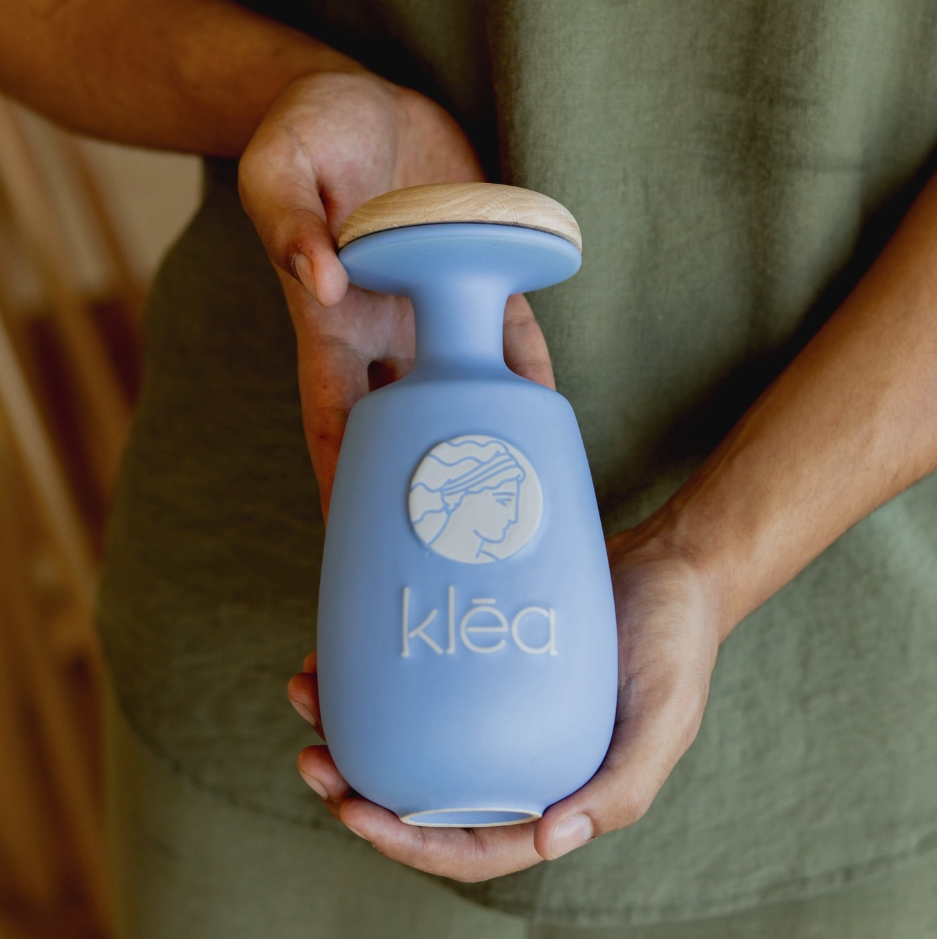 Klea natives Olivenöl extra Galani in blauer Keramikflasche mit Holzdeckel wird in beiden Händen gehalten